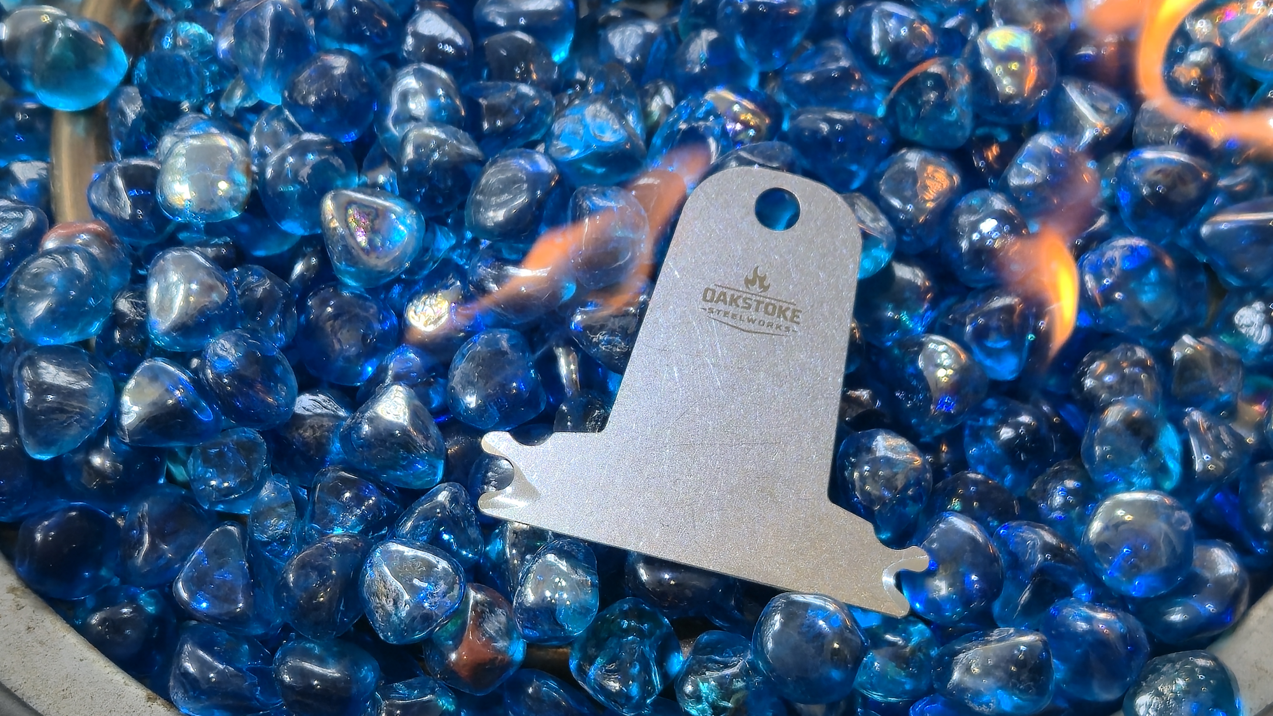 OakStoke bristle-free grill scraper in fire pit with blue glass stones, 304 stainless steel made in USA