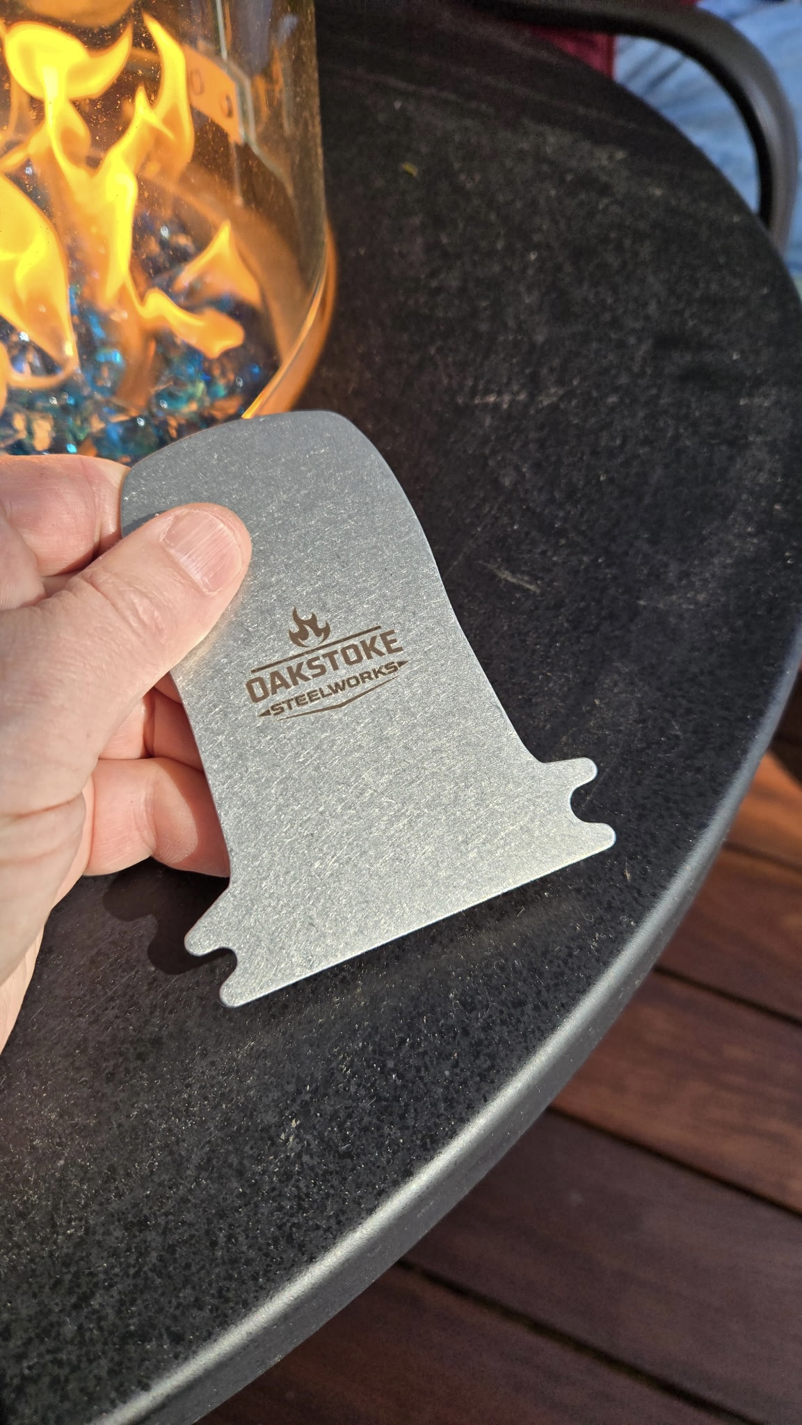 OakStoke bristle-free grill scraper held near open fire, 304 stainless steel, made in USA